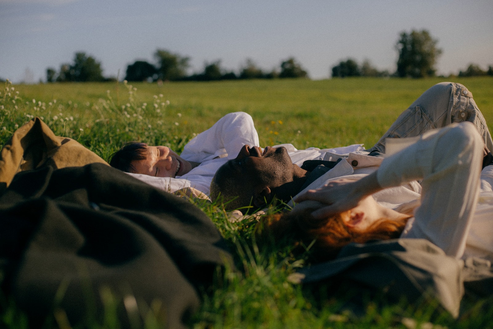 3 jeunes personnes rigolant dans l'herbe