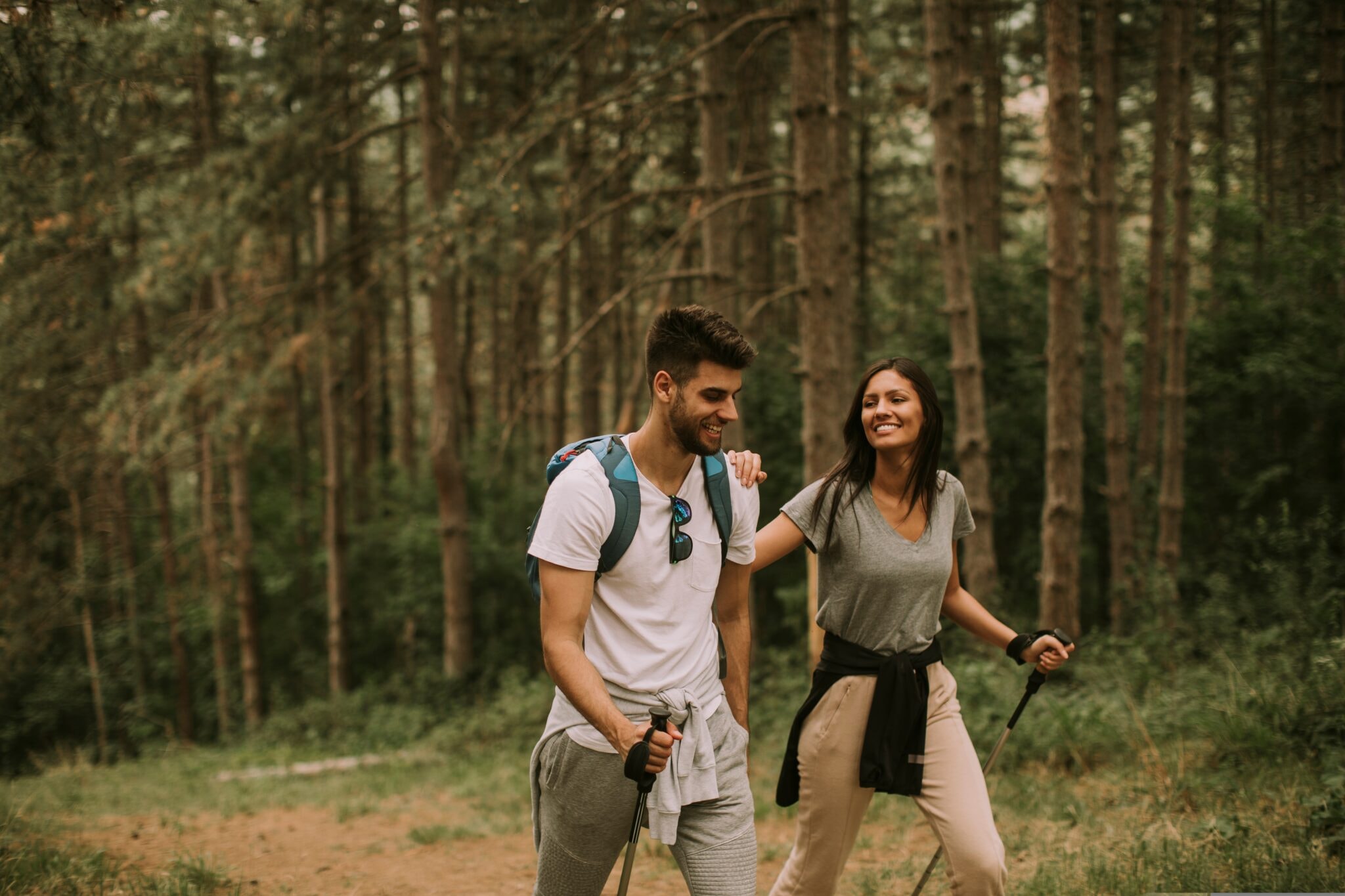 Couple,Of,Young,Hikers,With,Backpacks,Walk,Through,The,Forest