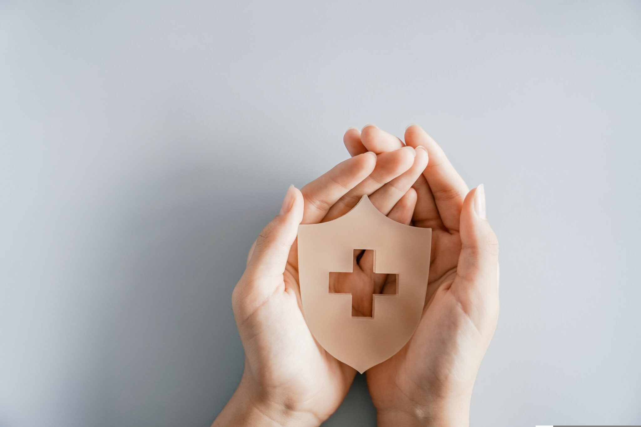 Hands,Holding,Shield,With,Cross,Sign,,Health,Insurance,,First,Aid,